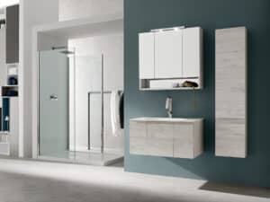Mobili bagno su misura in legno chiaro con lavabo integrato, pensili sospesi e box doccia in vetro trasparente. Design moderno ed elegante per un bagno raffinato.